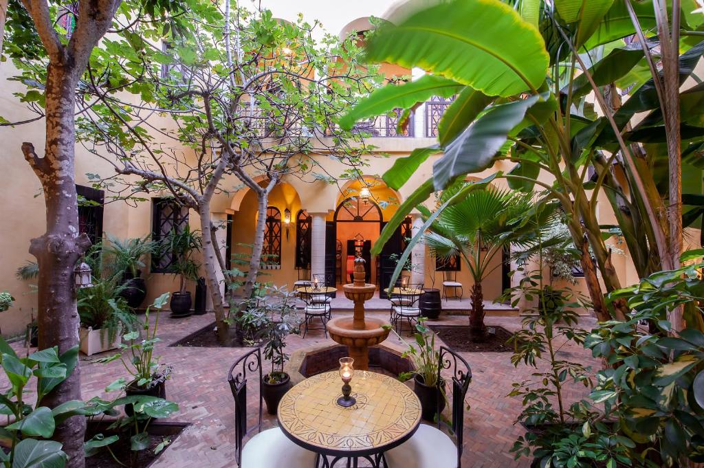 une cour avec une table, des chaises et des arbres dans l'établissement Riad Soleil D'orient, à El Jadida