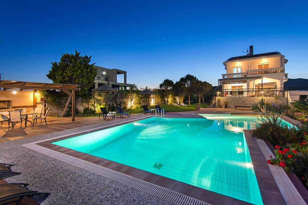 a swimming pool in front of a house at Alkyoni Villa in Lachania