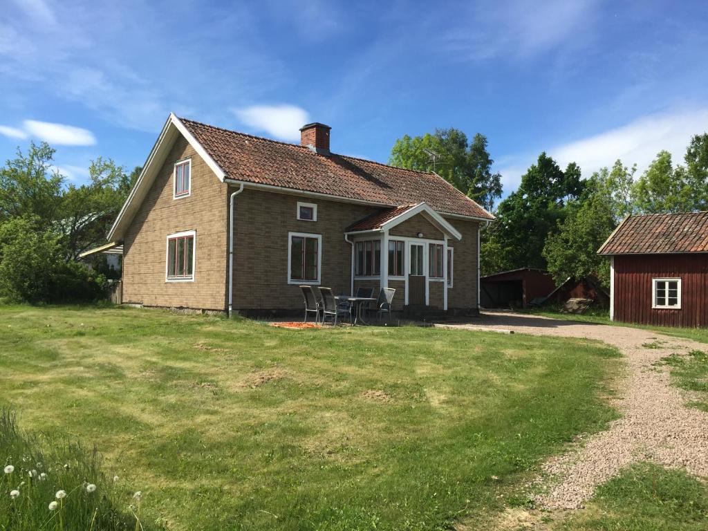 een klein huis met een grasveld en een huis bij Rolösa in Hjo