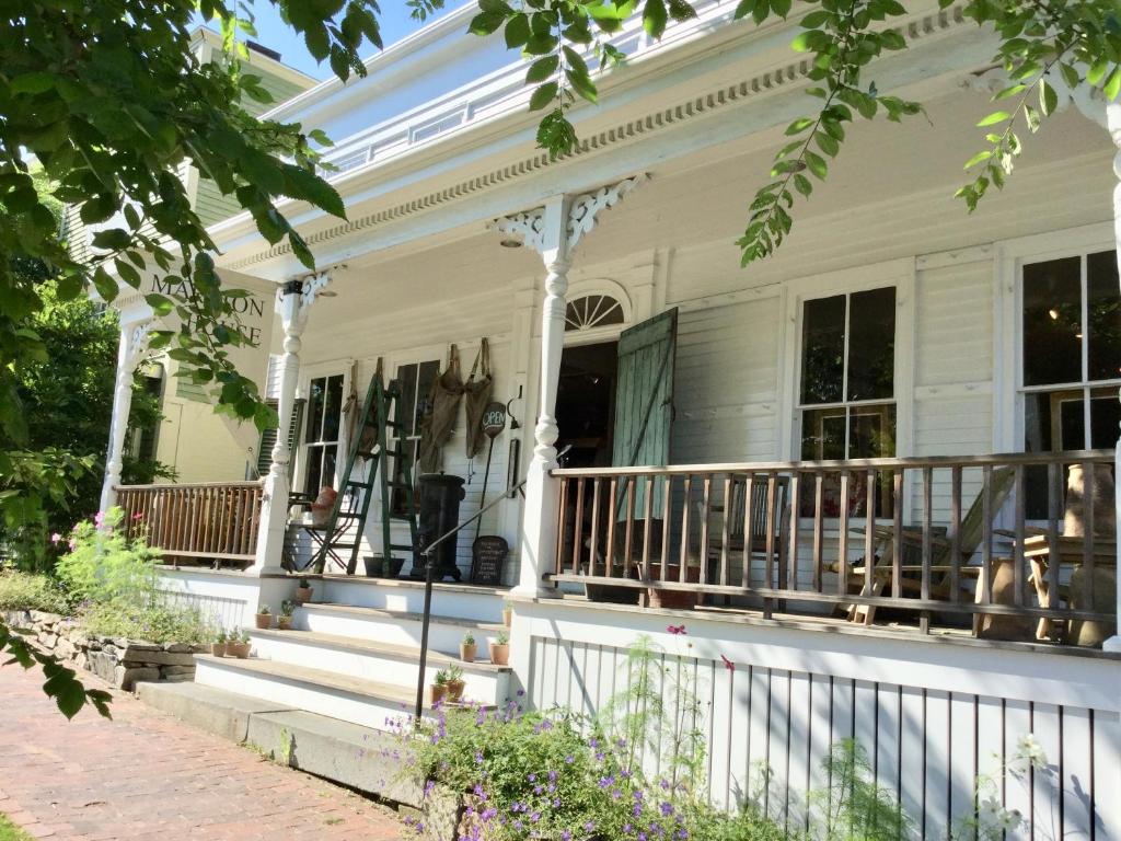 Cette maison blanche dispose d'une terrasse couverte avec une balustrade. dans l'établissement Marston House Wiscasset, à Wiscasset