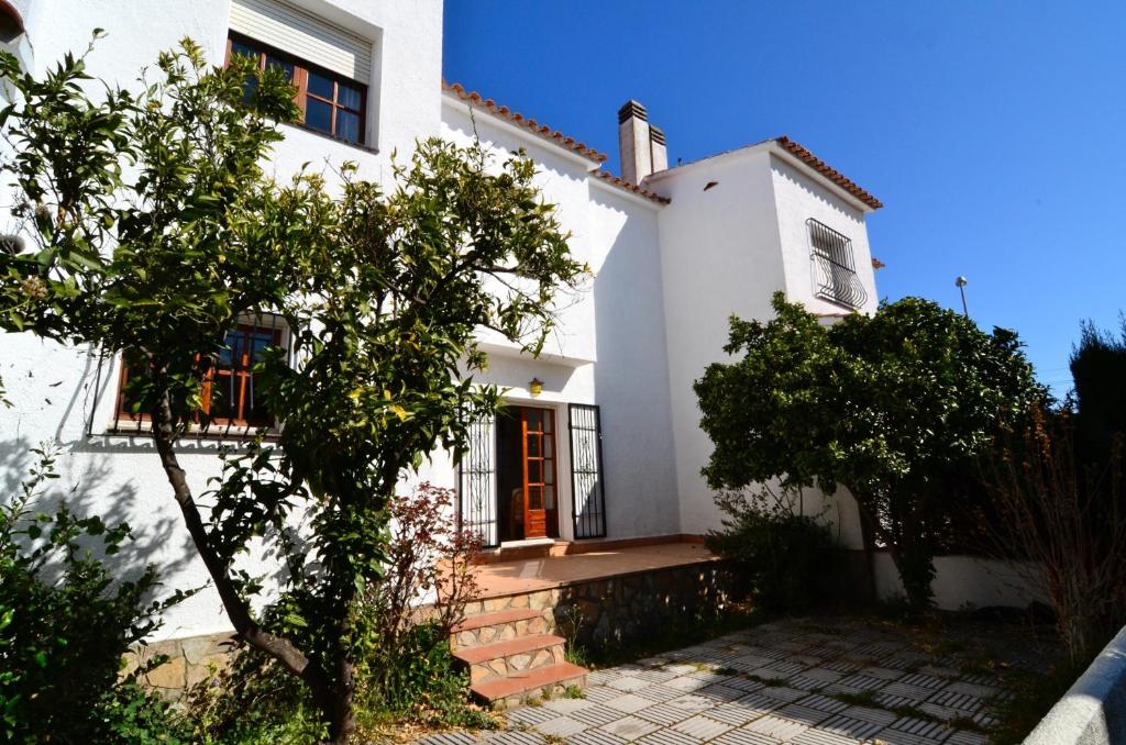 uma casa branca com uma árvore em frente em Casa la Flor em L'Escala
