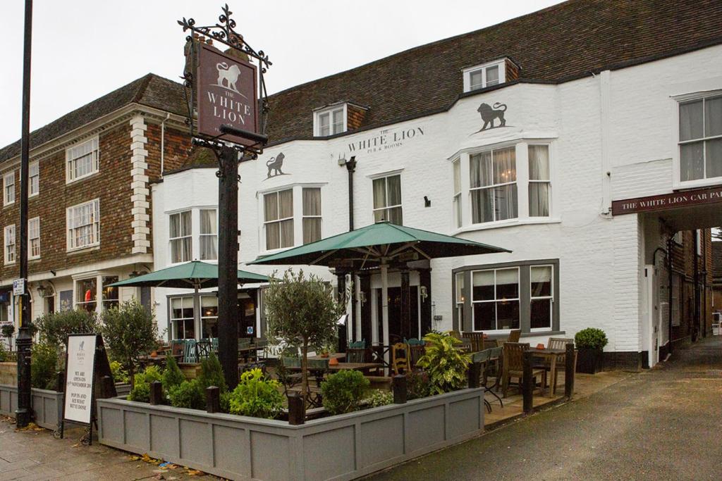 a hotel with tables and umbrellas in front of a building at The White Lion in Tenterden