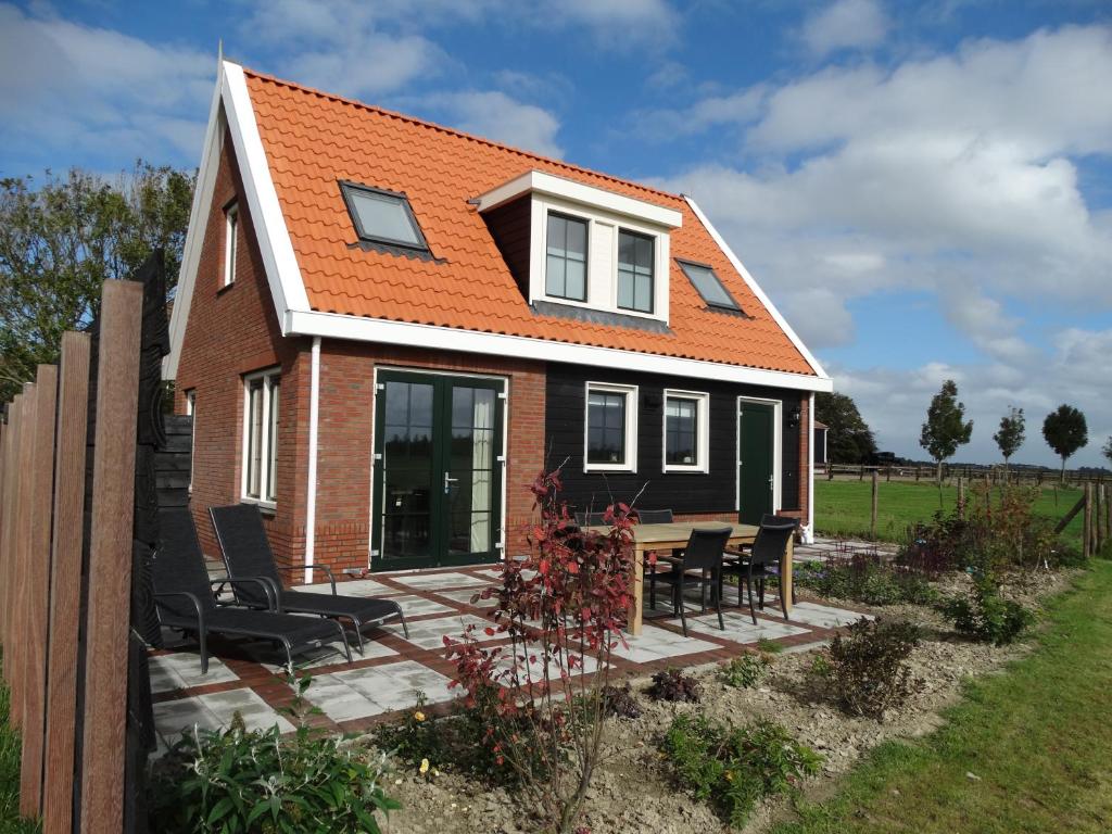 una casa con techo naranja en una terraza de madera en Vakantiehuis het Neerland, en Biggekerke