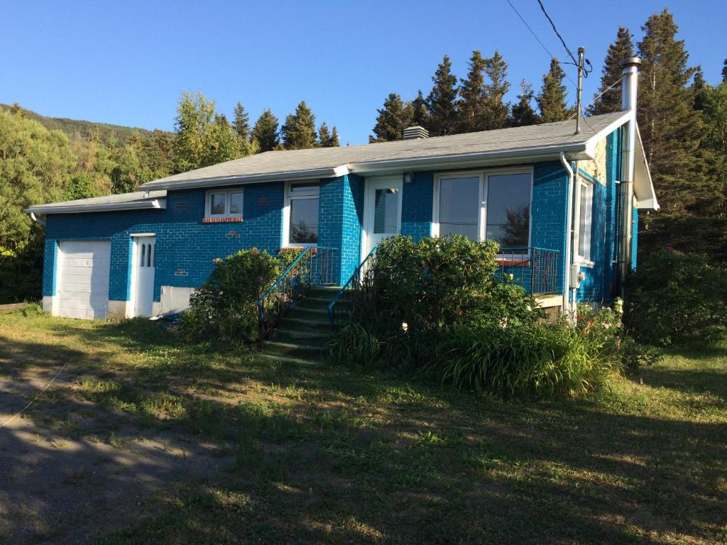 una casa azul con porche y patio en Maison Bleue en Sainte-Anne-des-Monts