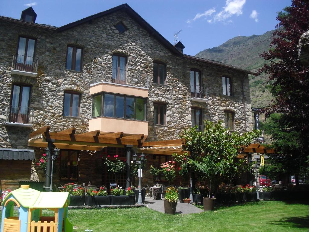 a large stone building with a playground in front of it at Hostal Vall D'Aneu by Arcas & Sambola in Esterri d'Àneu