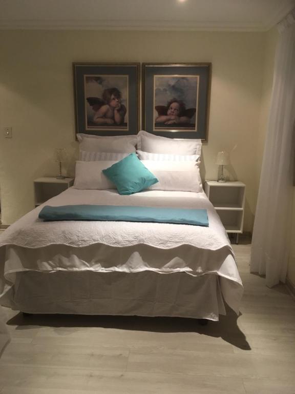 a bedroom with a large bed with two pictures on the wall at Sunninghill Sojourn in Kyalami
