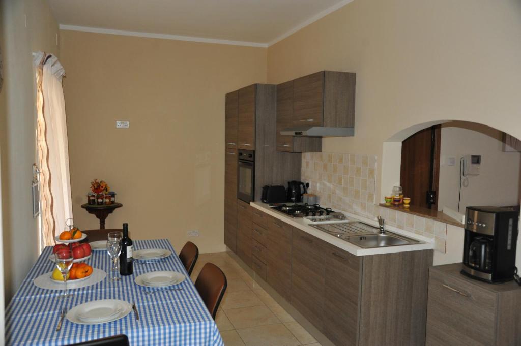 a kitchen with a table with a blue and white table cloth at Doms Apartment in Tarxien