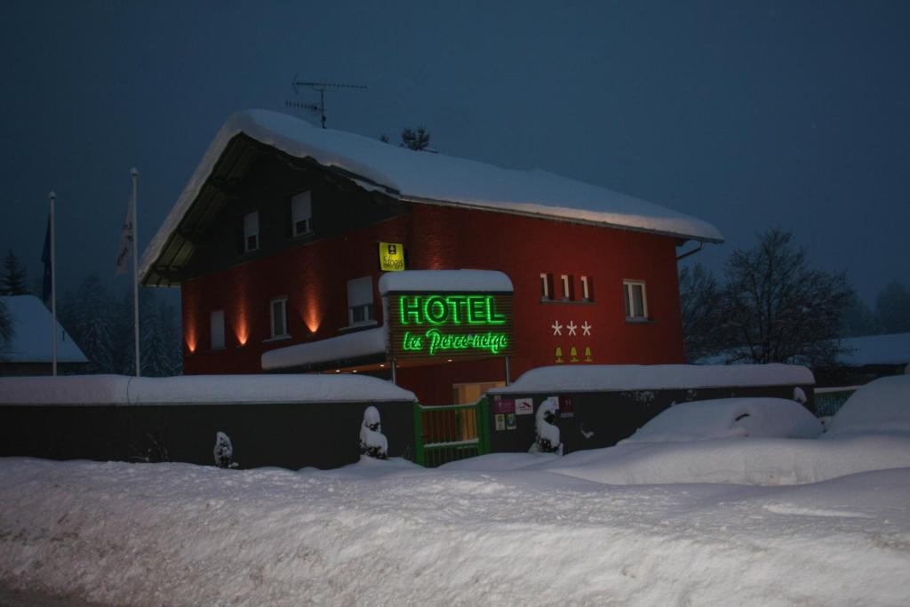 a red building with a sign on it in the snow at Hôtel Les Perce-Neige in Bonnétage
