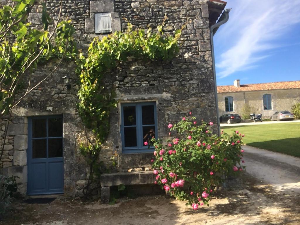 une maison en pierre avec une porte bleue et des fleurs dans l'établissement Les Gîtes de l'Astrée, à Saint-Bris-des-Bois