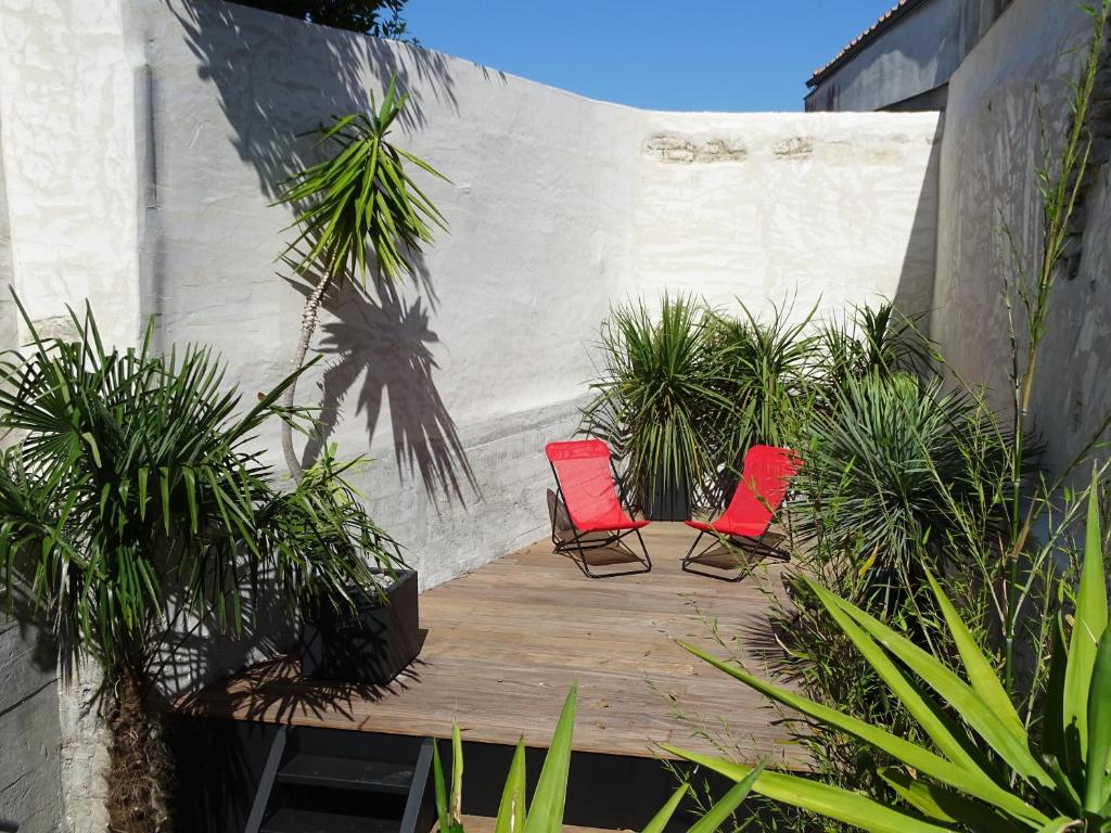 twee rode stoelen op een houten terras met planten bij Appartement Bastingage in Saint-Martin-de-Ré