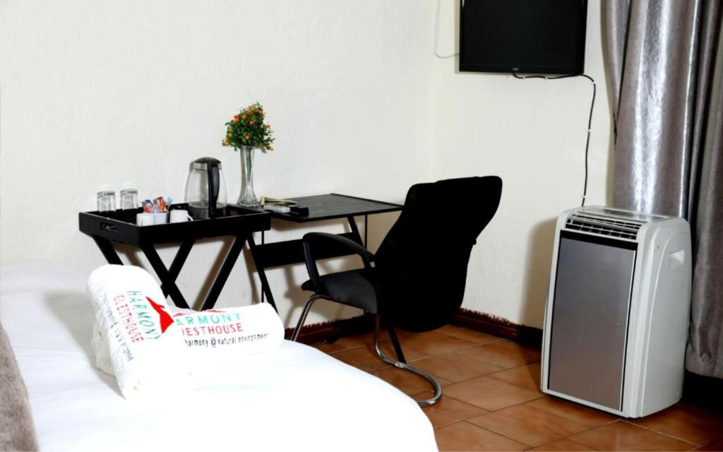 uma sala de estar com uma mesa e uma secretária com uma televisão em Harmony Guest House em Joanesburgo