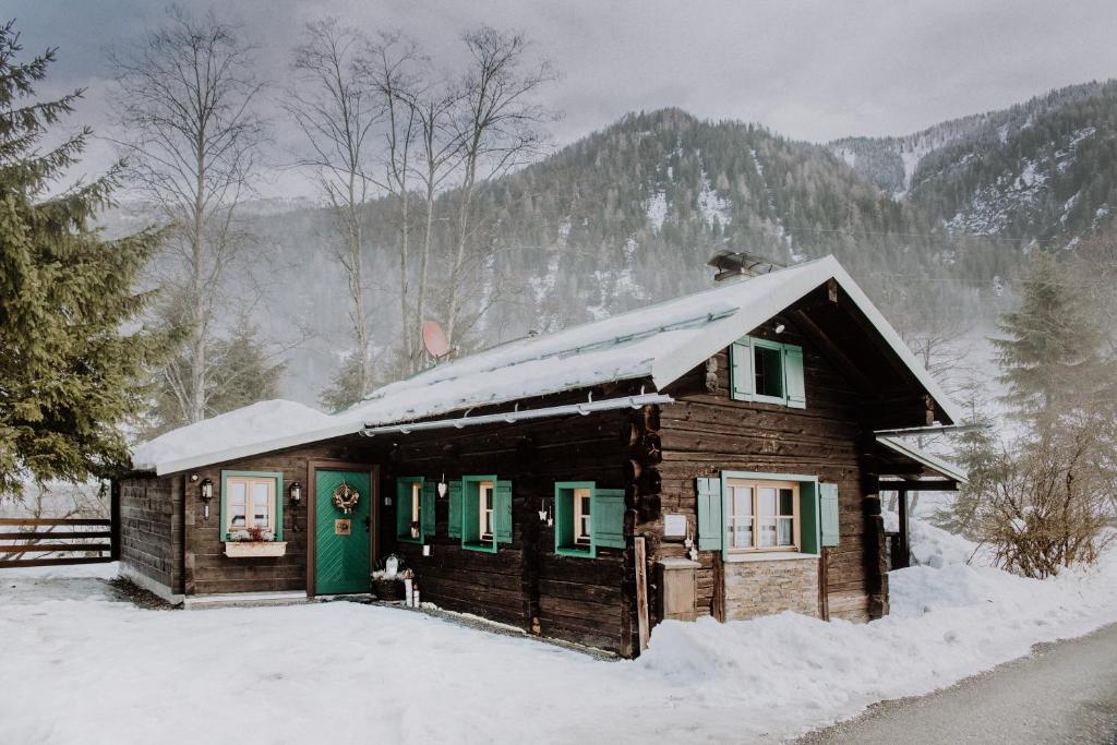 a wooden cabin with a green door in the snow at Knusperhauschen Sonnegg in Flachau