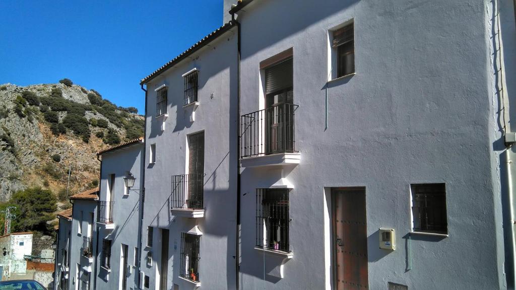 ein weißes Gebäude mit Fenstern und einem Berg im Hintergrund in der Unterkunft Apto rural Fuente El Chorrito de Grazalema in Grazalema