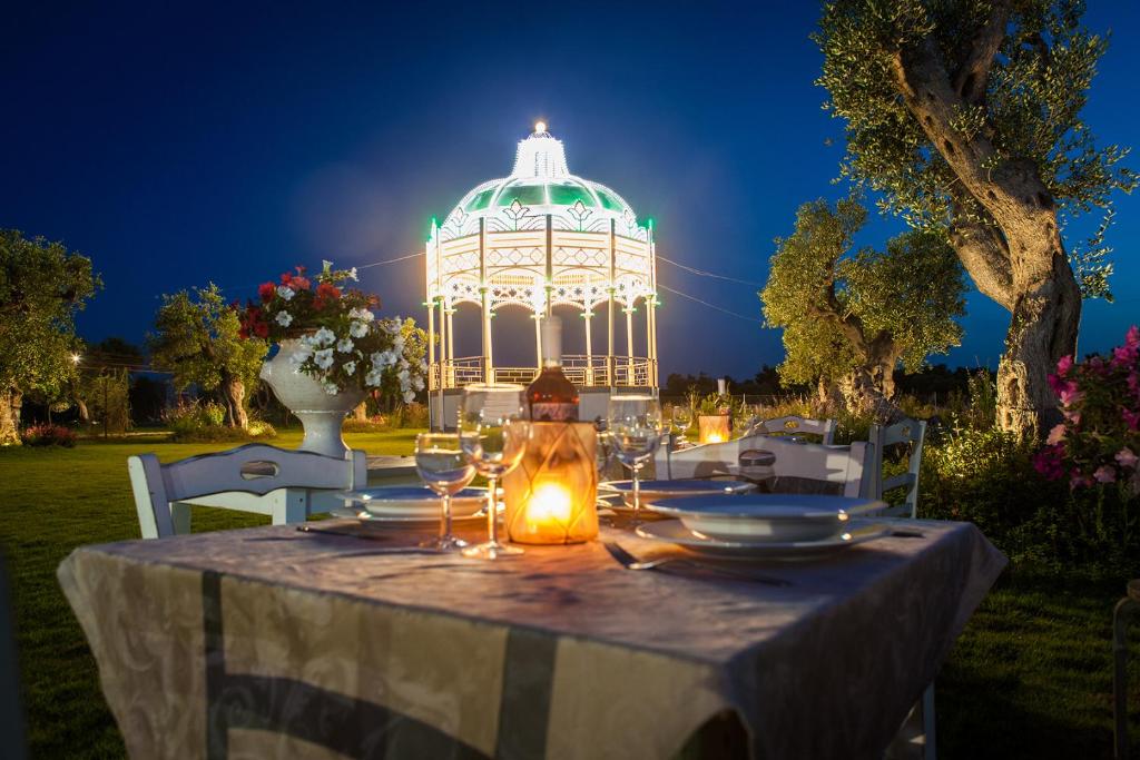 a table with wine glasses and a gazebo at night at Li Calizzi in Novoli