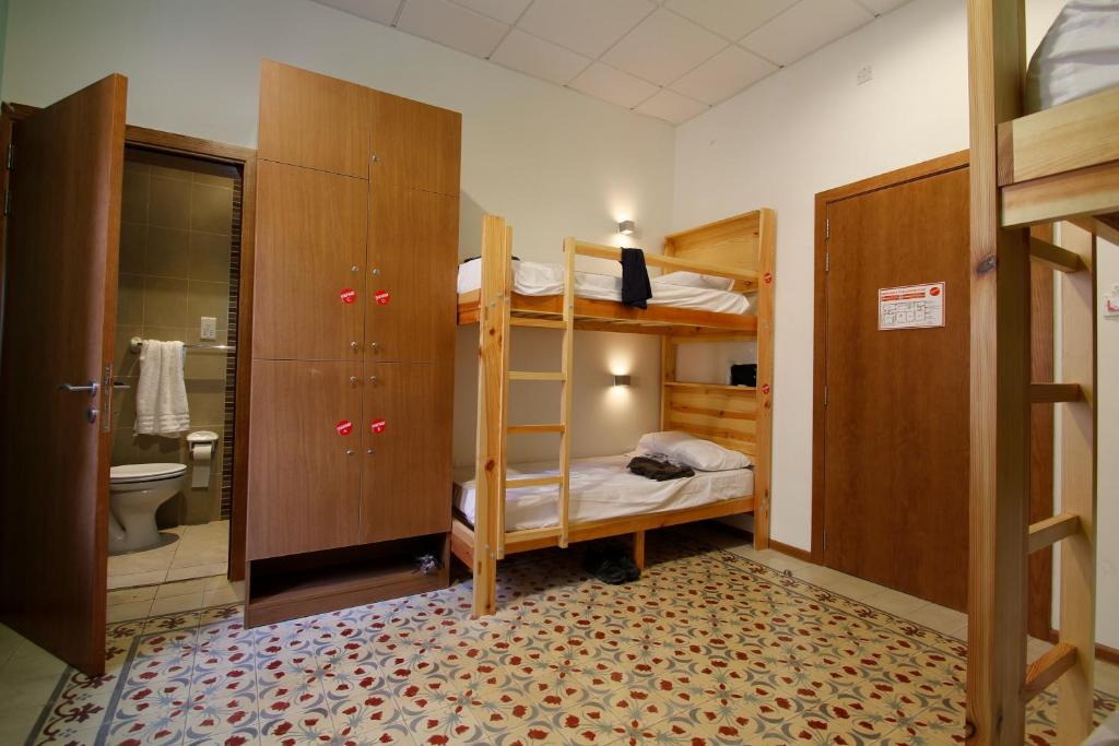 a bedroom with bunk beds and a bathroom with a toilet at Corner Hostel in Sliema