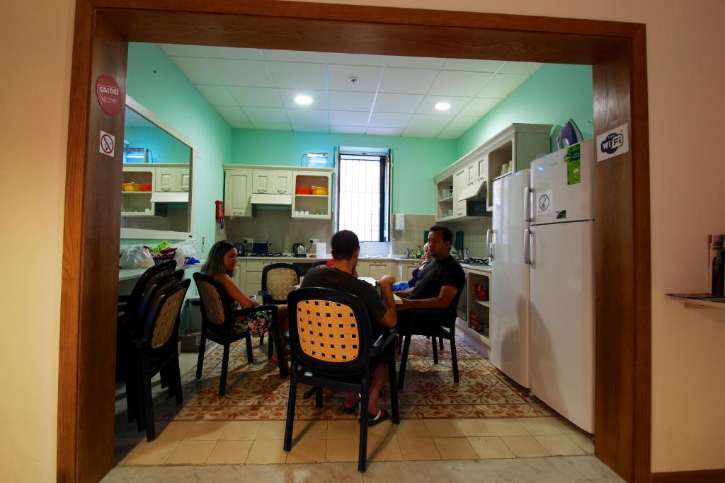 a group of people sitting at a table in a kitchen at Corner Hostel in Sliema
