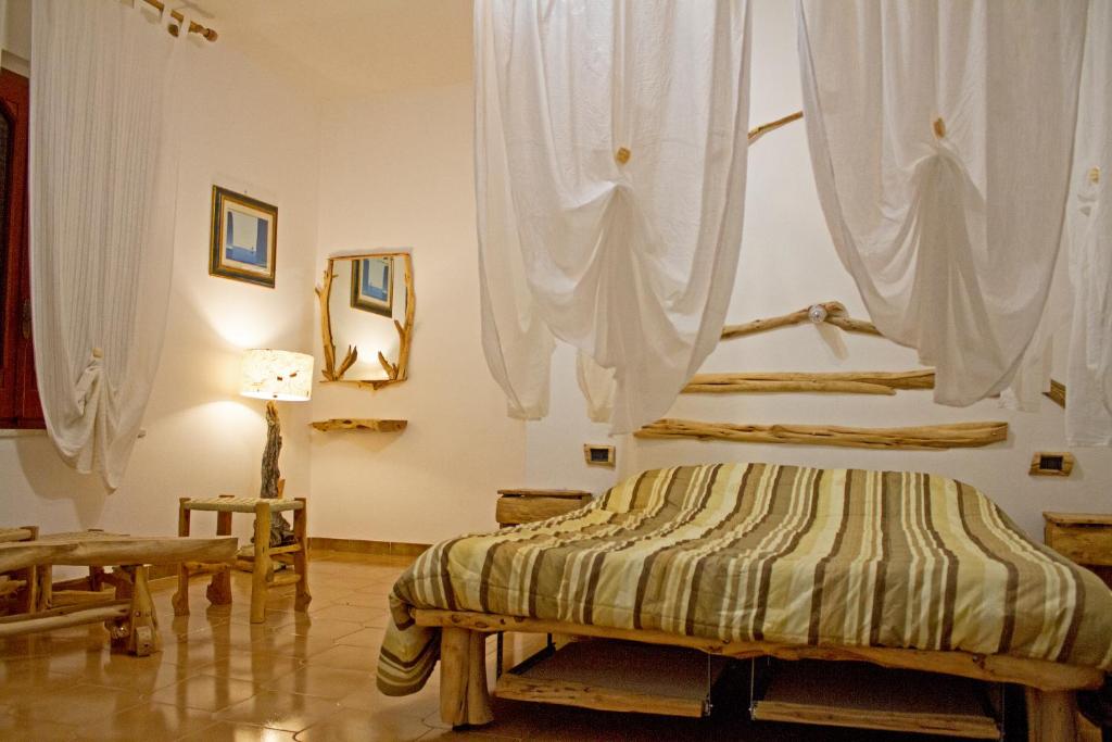 a bedroom with a bed with white curtains at B&B Wild Sardinia in Domusnovas