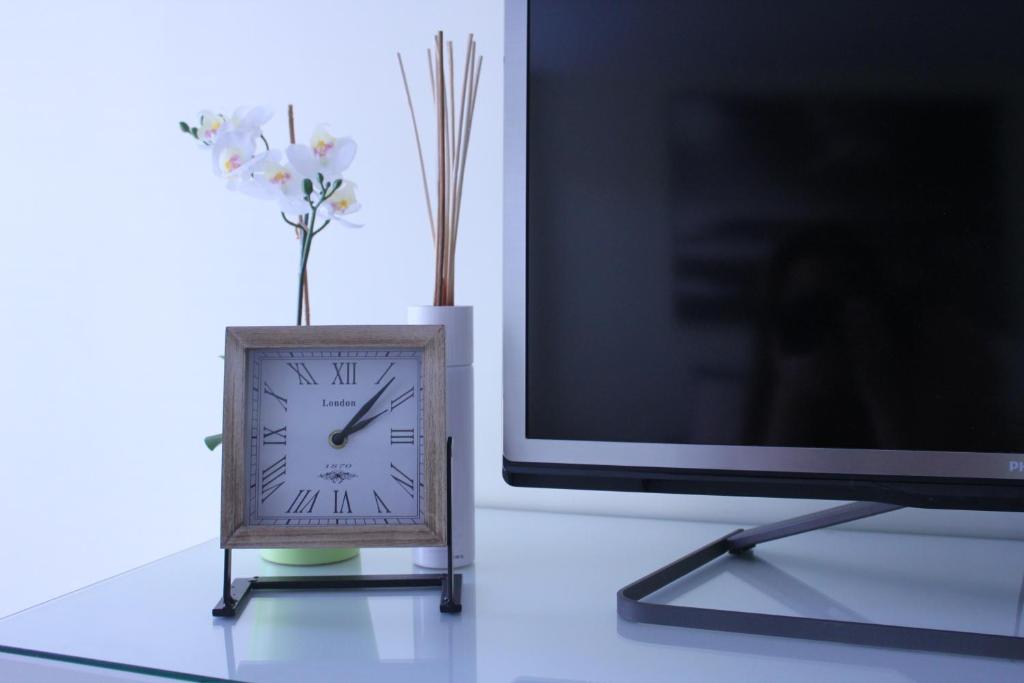 une horloge assise sur une table à côté d'une télévision dans l'établissement "meidoornhofje", à Nieuport
