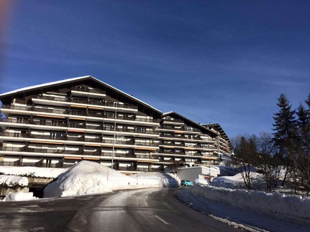 un gran edificio con nieve al lado de una carretera en Choucas A en Crans-Montana