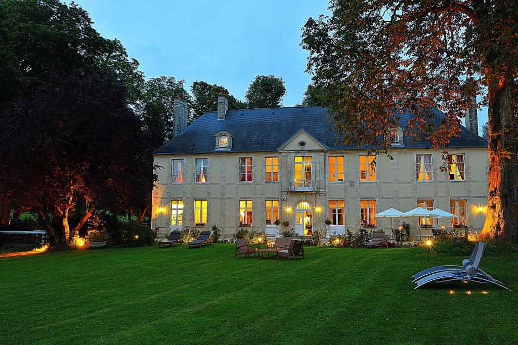 une grande maison avec une pelouse devant elle dans l'établissement Château de Bellefontaine - Teritoria, à Bayeux