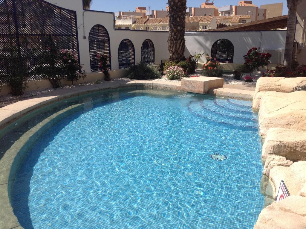 een zwembad met blauw water in een tuin bij Playamarina 1 Reception in Cabo Roig