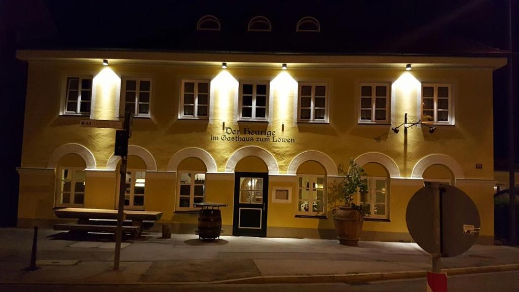 un grande edificio giallo con luci accese di notte di Der Heurige im Gasthaus zum Löwen a Freising