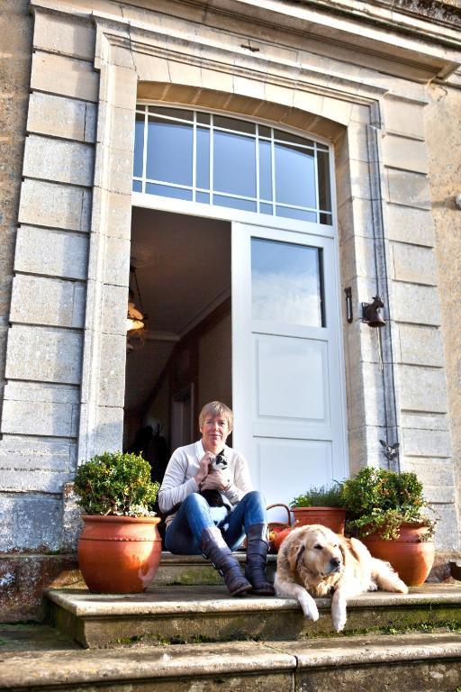 a man sitting on the steps with a dog at Chambres d&#39;Hôtes La Fresnée in Mosles