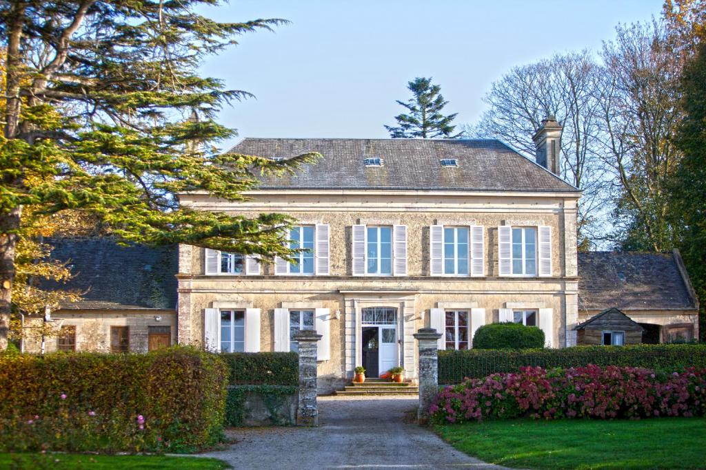 uma grande casa de pedra com uma entrada em Chambres d'Hôtes La Fresnée em Mosles