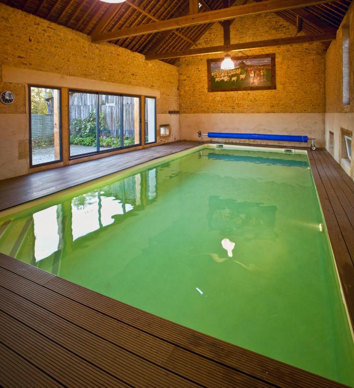 a large indoor swimming pool with green water at Chambres d&#39;Hôtes La Fresnée in Mosles