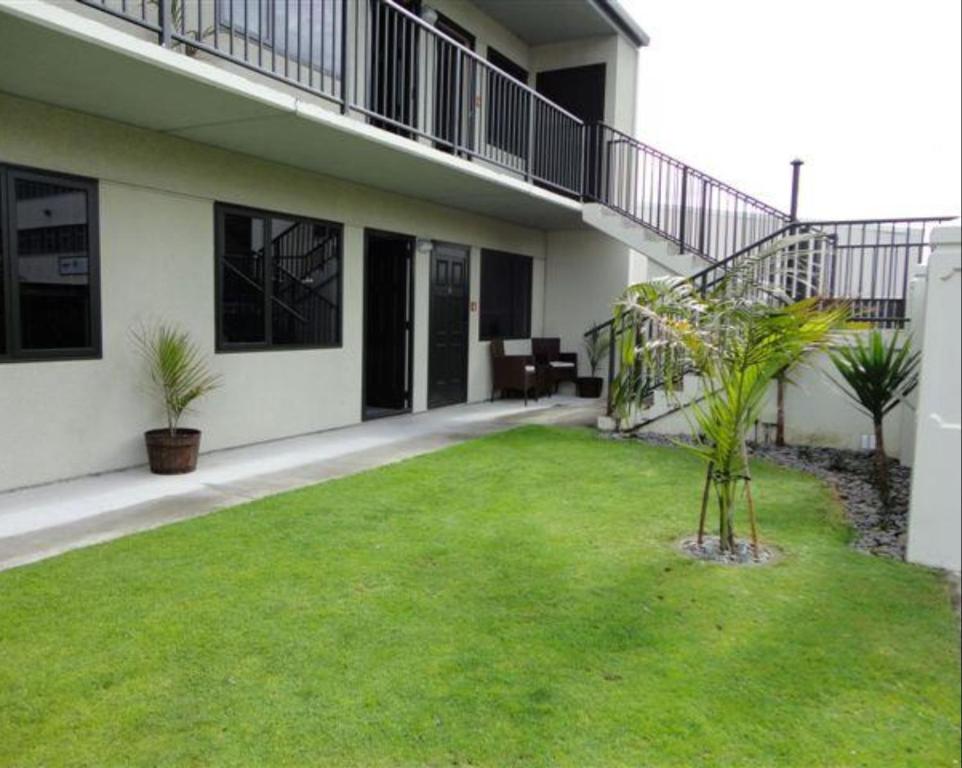 a house with a green lawn in the yard at ASURE Abode On Courtenay Motor Inn in New Plymouth