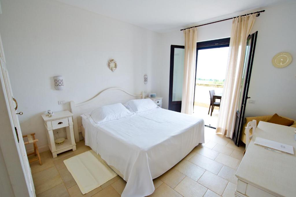 a white bedroom with a bed and a large window at Borgobianco Resort & Spa Polignano - MGallery Collection in Polignano a Mare
