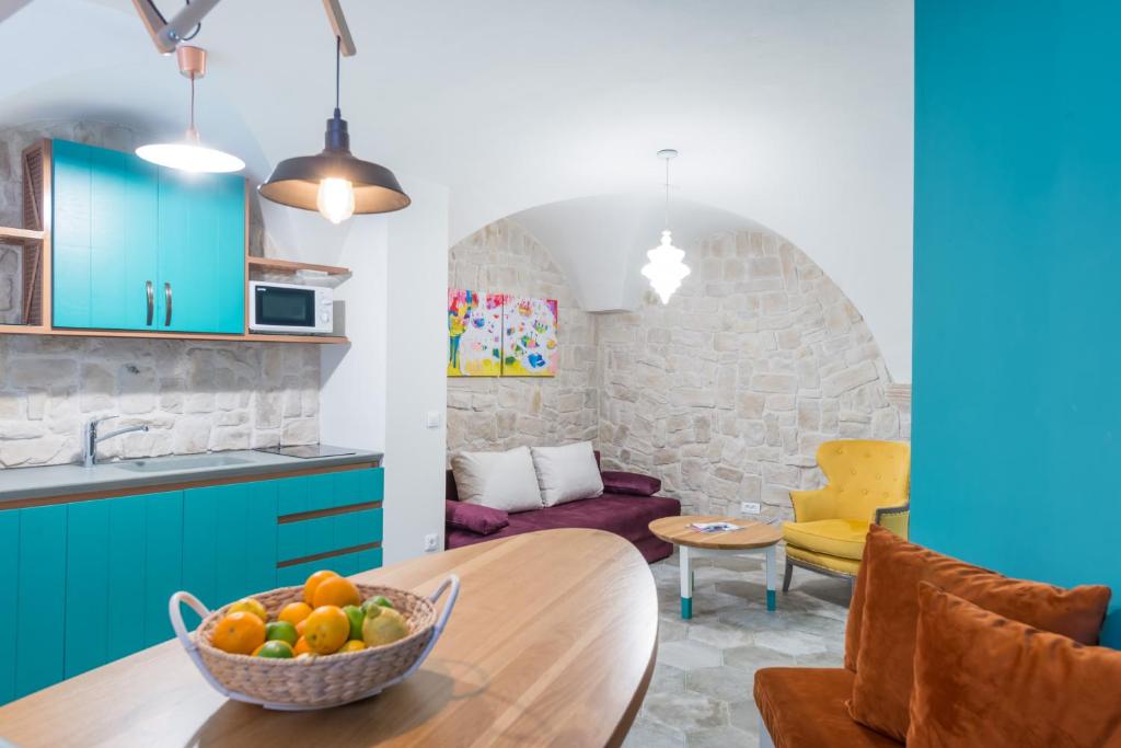 a kitchen with blue cabinets and a table with a bowl of fruit at Apartment Petra IV in Dubrovnik
