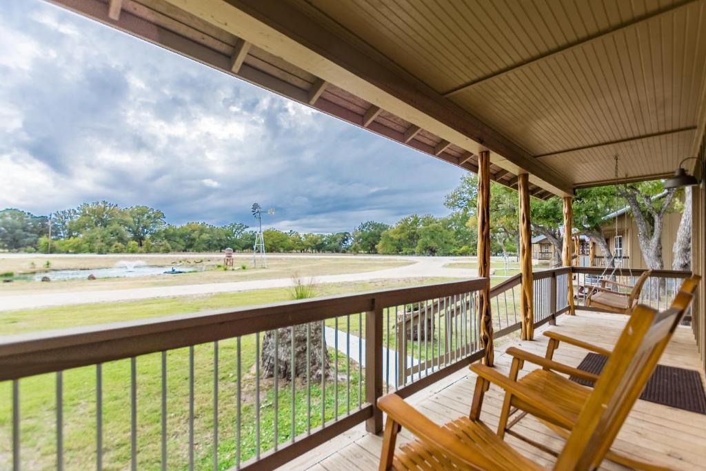 eine Veranda mit 2 Stühlen und Blick auf ein Feld in der Unterkunft Vineyard Trail Cottages- Adults Only in Fredericksburg