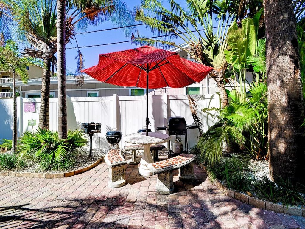 um pátio com uma mesa e um guarda-chuva vermelho em Palm Place 3 - Buccaneer Palm Beach getaway 622 em Clearwater Beach