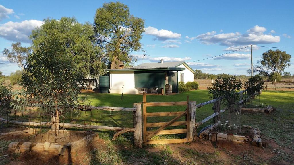 a house in the middle of a field with a fence at Charleville Bush Cottage in Charleville