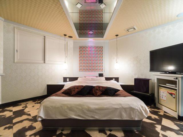 um quarto com uma cama e uma televisão de ecrã plano em Hotel TiAMO (Love Hotel) em Kitakyushu