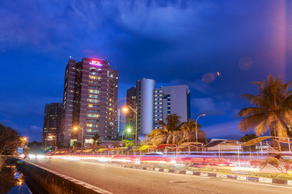 een skyline van de stad 's nachts met hoge gebouwen bij Beta Service Apartment in Labuan