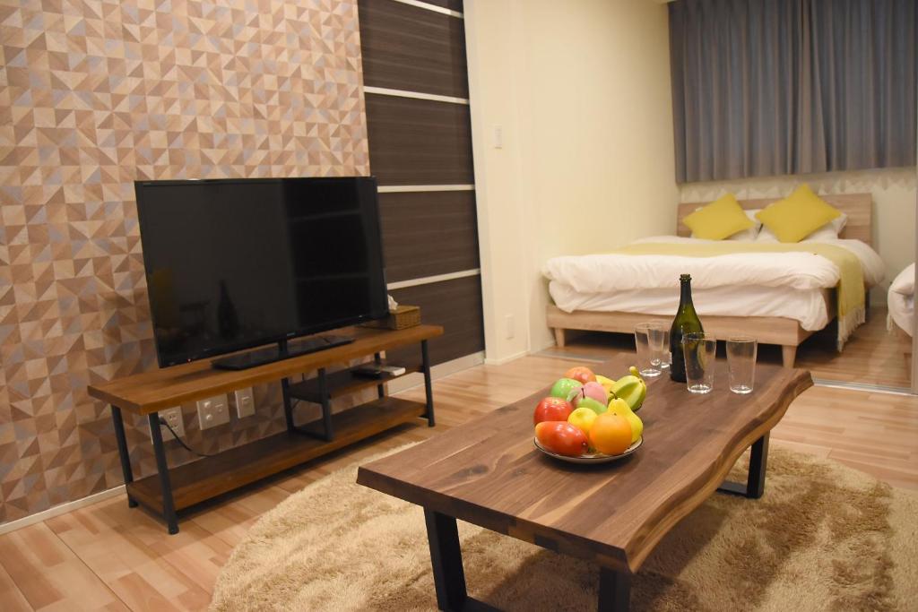 a living room with a television and a table with a bowl of fruit at Ambiera Doza in Nagasaki