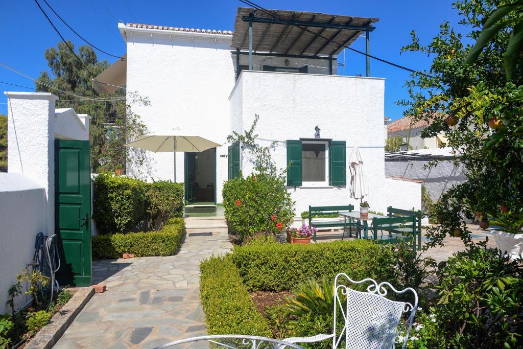 ein weißes Haus mit einer grünen Tür und einer Terrasse in der Unterkunft Villa Anesis in Spetses