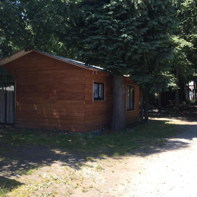 a small cabin with a tree in front of it at Cabañas El Portal in Neltume