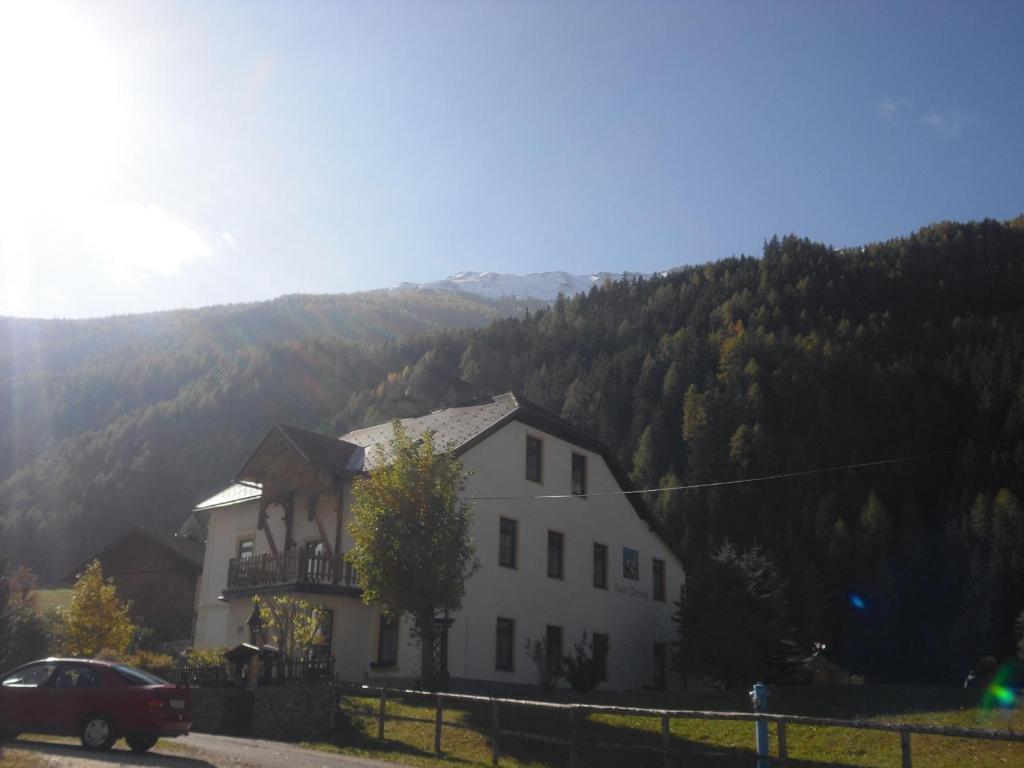 a white house in the mountains with a car parked in front at Haus Obernig in Mallnitz