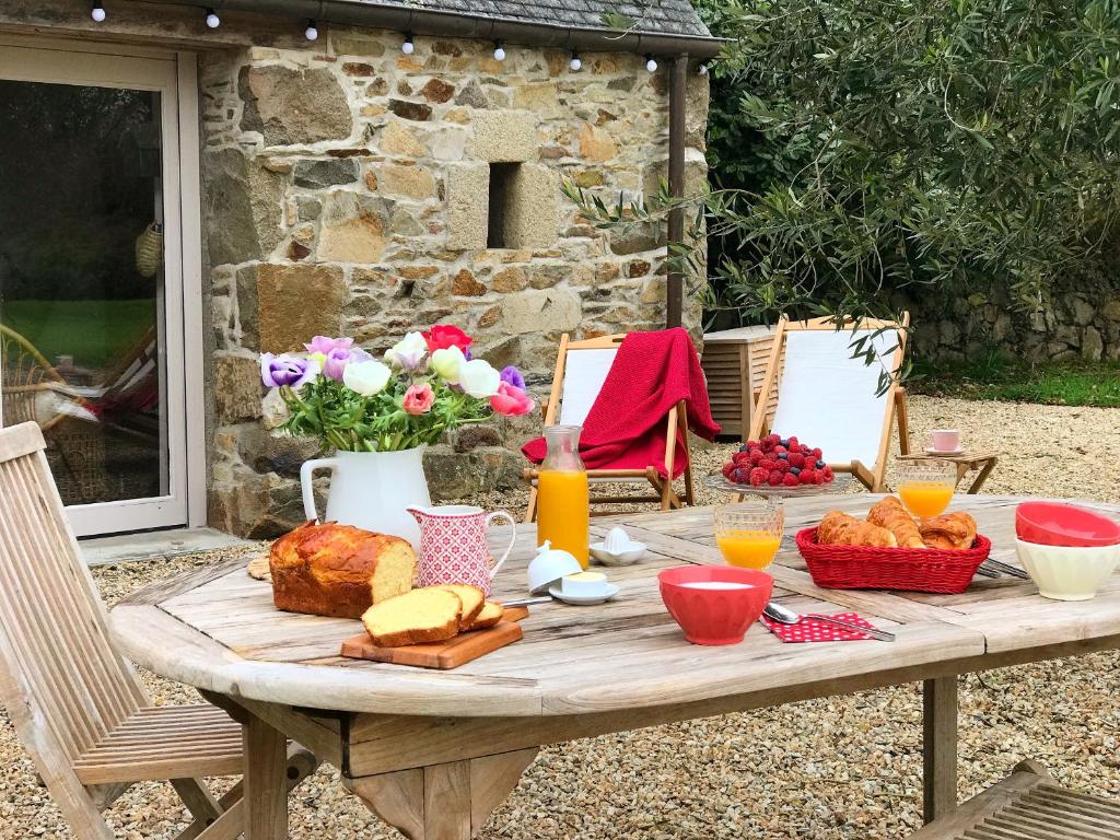 a picnic table with bread and orange juice on it at Manoir des petites bretonnes in Saint-Quay-Perros