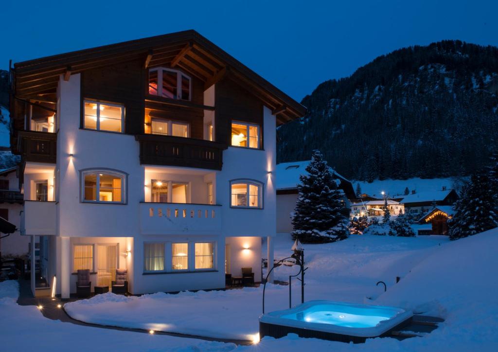 a building with a hot tub in the snow at Apartments Antines in Selva di Val Gardena