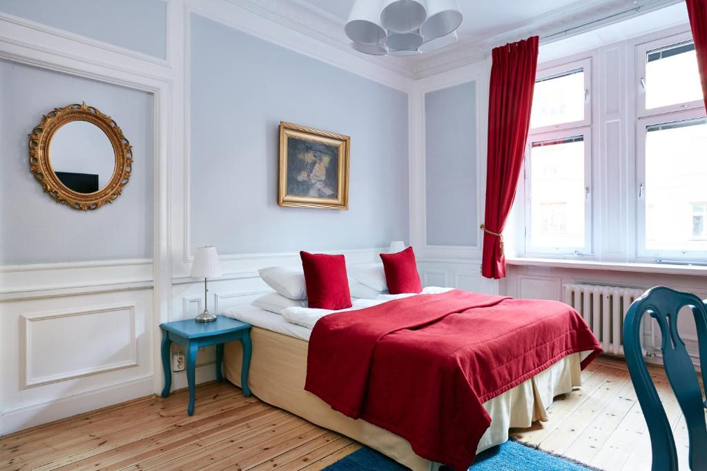a bedroom with a bed with red sheets and a mirror at Hotel Hornsgatan in Stockholm