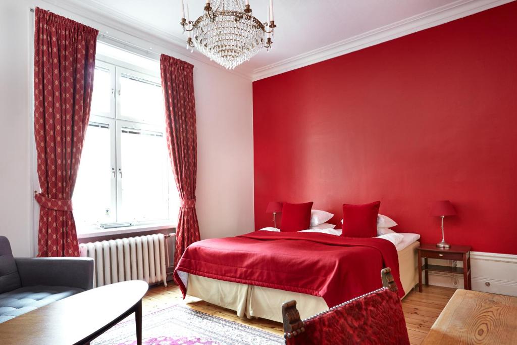a red bedroom with a bed and a chandelier at Hotel Hornsgatan in Stockholm