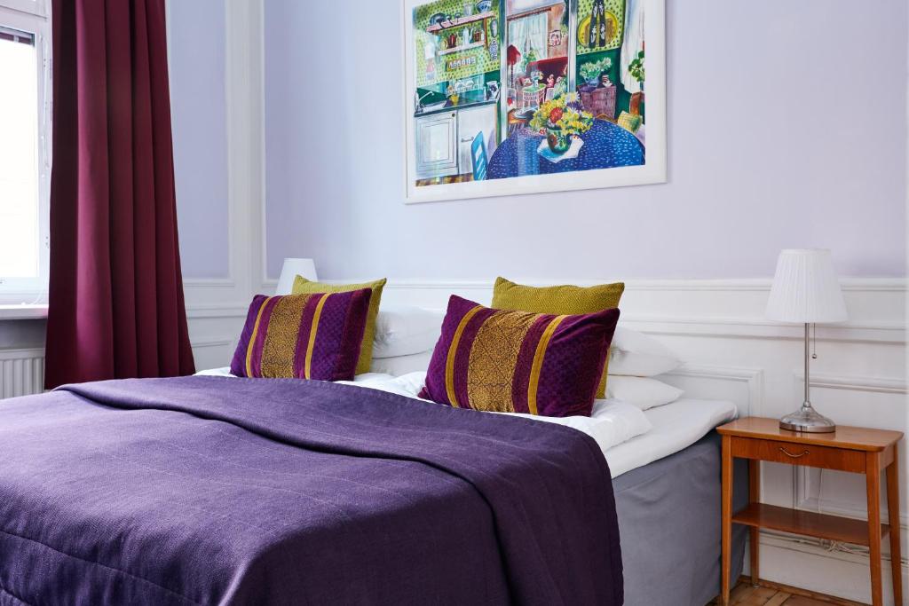 a bedroom with a bed with a purple blanket at Hotel Hornsgatan in Stockholm