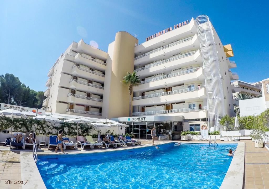 a hotel with a swimming pool in front of a building at Apartamentos Ponent in Paguera