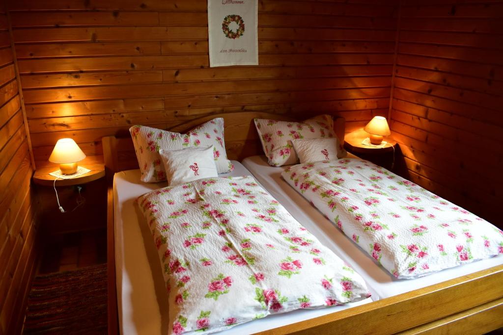 two beds in a wooden room with two lamps at Ellernhof im Spessart in Stadtprozelten