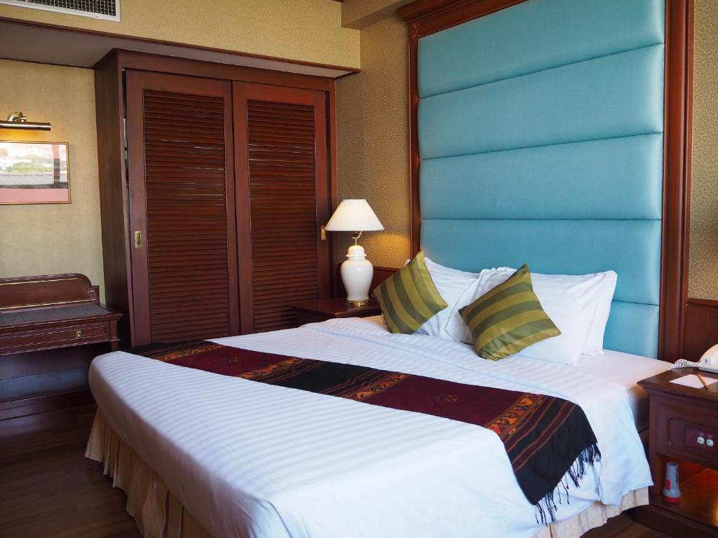 Schlafzimmer mit einem großen Bett mit blauem Kopfteil in der Unterkunft Charoen Thani Hotel, Khon Kaen in Khon Kaen