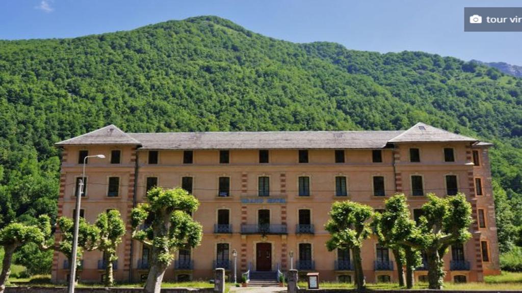 un grand bâtiment avec des arbres devant une montagne dans l'établissement Appartement à la montagne, à Aulus-les-Bains